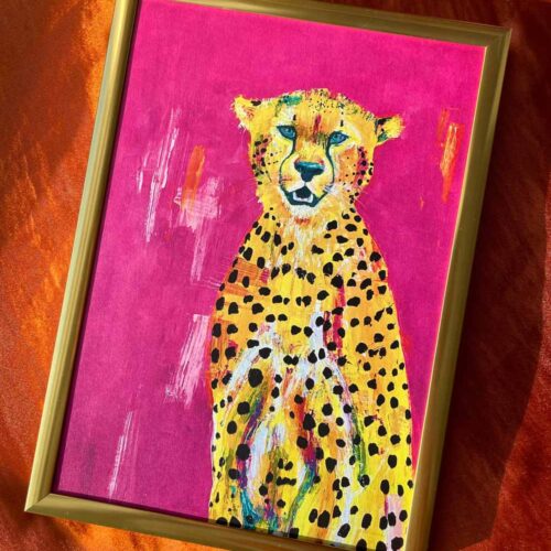 Yellow and pink cheetah framed in a gold frame sat on an orange satin background