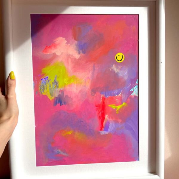 hand holding a very colourful abstract art with happy face.
