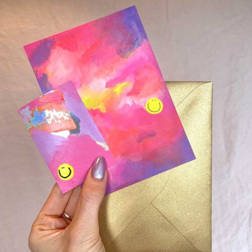 hand holding Colourful holographic vinyl sticker and abstract art print both with happy faces