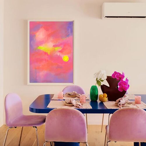 glimmers print which is pink peach and lilac painting with happy face hung above a blue dining table with lilac chairs