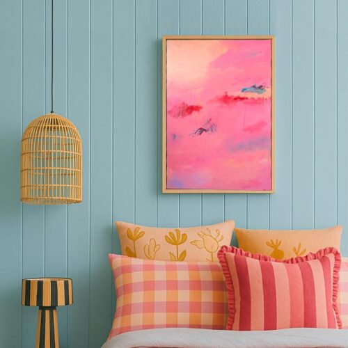 Pink red and blue abstract art above a pink and blue patterened bed with cushions