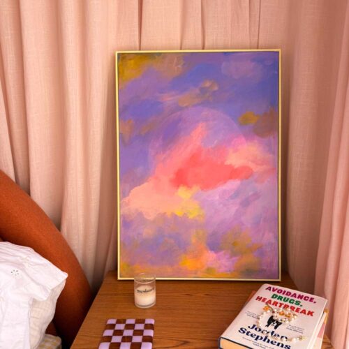 colourful abstract moon in a yellow frame sat on a bedside table