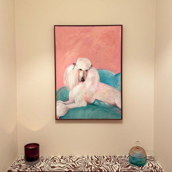Fancy Poodle Art print. Painting of a standard poodle reclining on a blue sofa hung on a neutral wall.